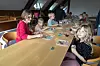 Eine lange Tafel, Kinder sitzen jeweils links und rechts am Tisch. Vor Ihnen ihre Tonkunstwerke auf kleinen Plastikdeckeln.