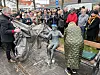 Menschenmenge beobachtet die Enthüllung der Skulptur „Forundringsparat“ auf einer Bank an der Strandpromenade.