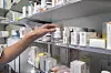 Eine Person greift ein Medikament aus dem Regal einer Apotheke