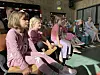 Kinder sitzen auf Stuhlreihen im Publikum