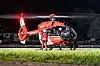 DRF-Rettungshubschrauber bei Nachtlandung auf beleuchteter Wiese mit Einsatzkraft davor