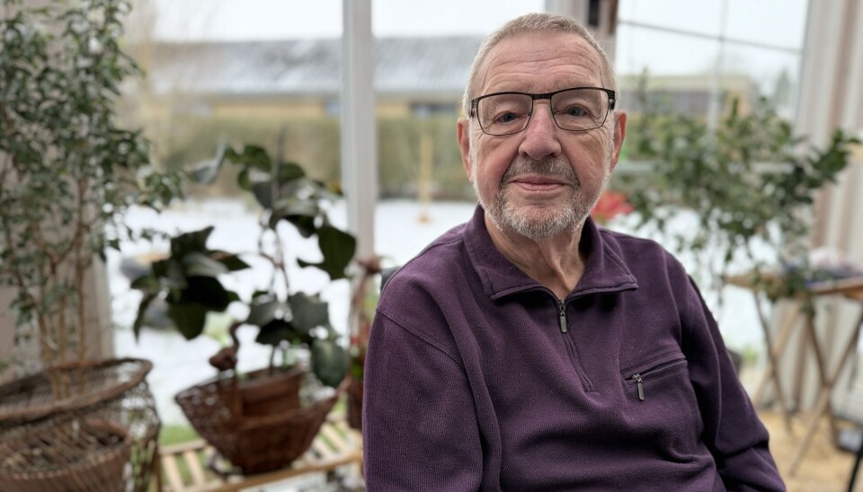 Walter Brüning in seinem Wintergarten in Ulderup Älterer Mann mit Brille sitzt im Wintergarten vor einem Tisch, hinter ihm mehrere Zimmerpflanzen.