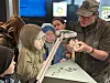 Geologe zeigt einer Gruppe von Kindern im Museum Fossilien unter einer Lupenlampe.