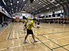 Jugendliche spielen 2x2-Faustball in einer großen Sporthalle mit mehreren Feldern.