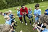 Trainer der HSV-Fußballschule steht mit Kindern im Kreis auf einem Rasenplatz.