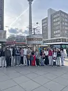 Schulgruppe steht am Alexanderplatz vor der Weltzeituhr und dem Berliner Fernsehturm.