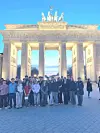 Gruppe Jugendlicher steht abends vor dem beleuchteten Brandenburger Tor in Berlin.