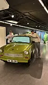 Zwei Jugendliche stehen in einem Museum neben einem grünen Trabant.