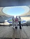 Drei Jugendliche posieren auf einer Tribüne im Berliner Olympiastadion mit Blick auf Spielfeld und Ränge.