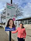 Frau steht neben deutschsprachigem Wahlplakat der Partei Radikale Venstre an einer Straße.