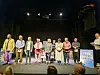 Mehrere Darsteller in Kostümen stehen nebeneinander auf einer Theaterbühne.