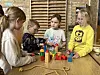 Mehrere Kinder bauen gemeinsam bunte Holzklötzchen auf einem Tisch.