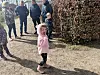 Kind in rosa Jacke geht auf einem Schulhof, Erwachsene und weitere Kinder im Hintergrund.