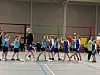 Jugendhandballer in blauen Trikots klatschen sich nach dem Spiel in einer Sporthalle ab.