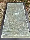 Metallne Gedenkplatte mit der Jahreszahl 1945 und eingravierten Namen auf Steinpflaster.