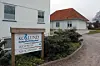 Eingangsschild des Privathospitals Kollund vor weißem Klinikgebäude mit Kiesweg.