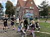 Kinder und Jugendliche laufen gemeinsam auf einem Schulhof vor einem roten Backsteingebäude.