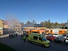 Feuerwehr- und Rettungsfahrzeuge vor rauchendem Gebäude im Tageslicht